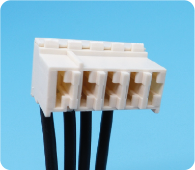 Primo piano di un connettore elettrico rettangolare bianco a quattro pin con fili neri collegati, su uno sfondo azzurro.